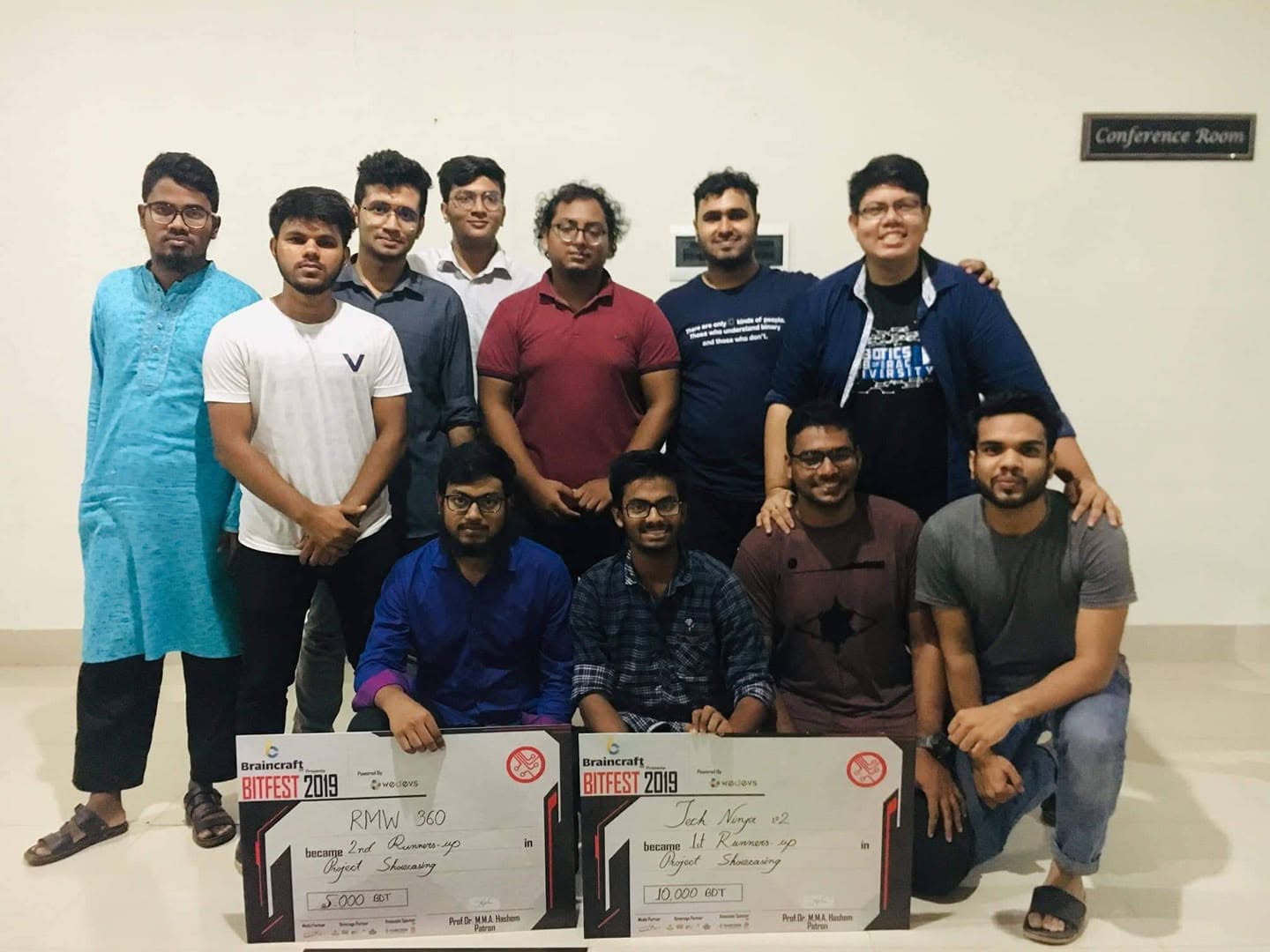 Eleven students standing together behind two BitFest 2019 prize cheques for the RMW 360 and Tech Ninja v2 projects.
